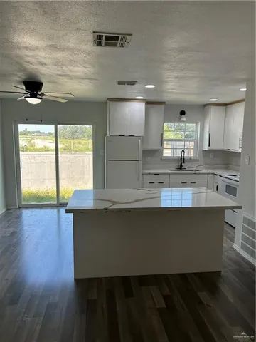 a kitchen with kitchen island a sink wooden floor and a large window