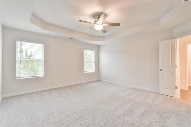 an empty room with windows and fan