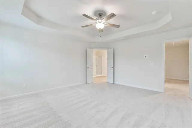 wooden floor in white room with a ceiling fan and window