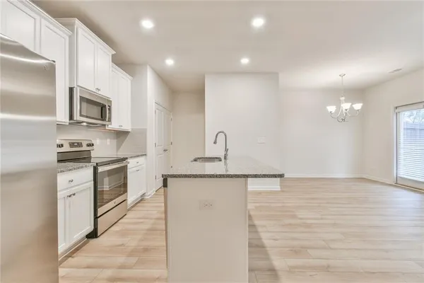 a large kitchen with granite countertop a stove a sink and a refrigerator