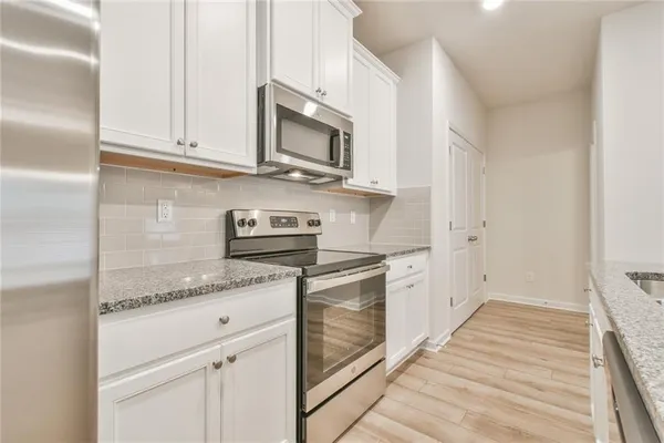 a kitchen with stainless steel appliances granite countertop white cabinets and white appliances