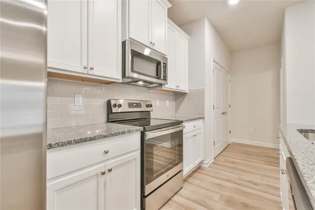 a kitchen with stainless steel appliances granite countertop white cabinets and white appliances