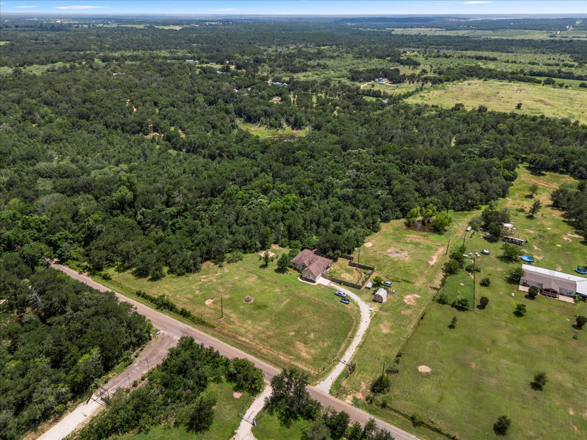 437 Balch Road Elgin, TX 78621 - Photo 31 of 37 An aerial perspective reveals a vast expanse of verdant landscape with scattered homes and a winding driveway.