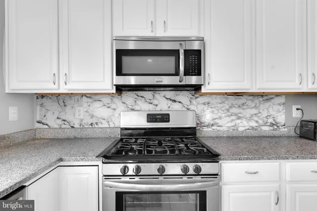 a kitchen with granite countertop white cabinets and stainless steel appliances