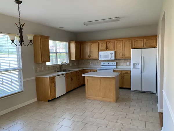 a kitchen with stainless steel appliances granite countertop a refrigerator a sink a stove a washer and a window