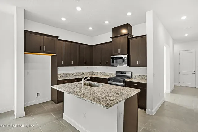 a kitchen with granite countertop kitchen island stainless steel appliances a sink refrigerator and microwave