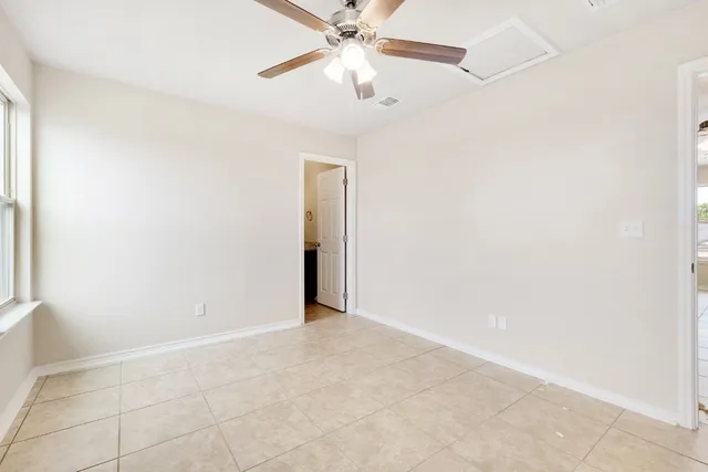 an empty room with chandelier fan and windows