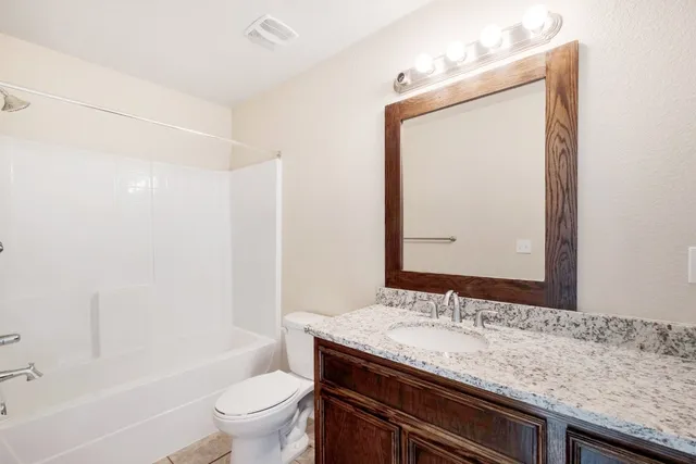 a bathroom with a granite countertop sink a toilet and a mirror