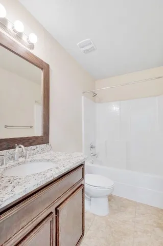 a bathroom with a granite countertop sink a toilet and a bathtub