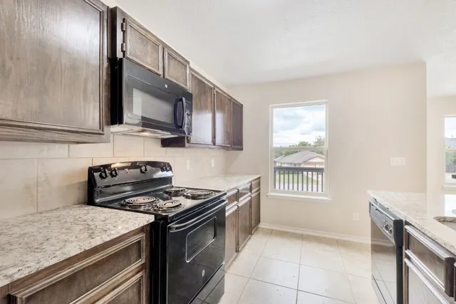 a kitchen with stainless steel appliances granite countertop a stove a sink and a microwave