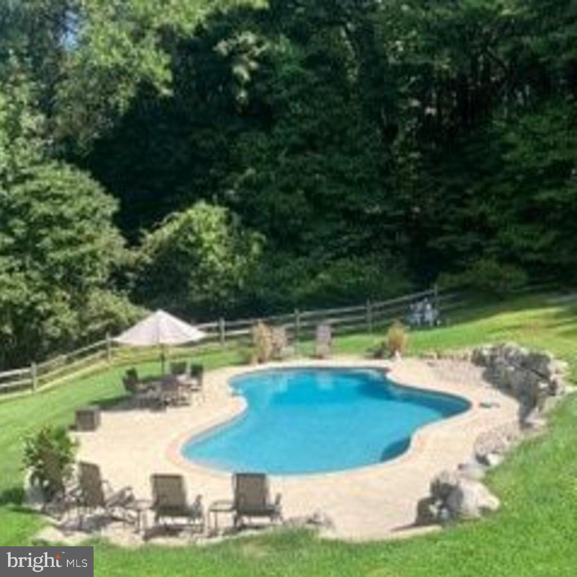 46 Wetzel Road Macungie, PA 18062 - Photo 39 of 42 a view of a swimming pool with lawn chairs under an umbrella