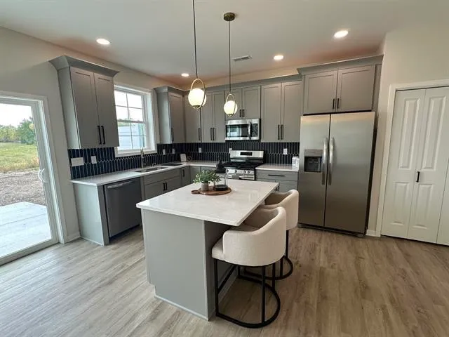 a kitchen with stainless steel appliances a sink a stove a refrigerator cabinets and wooden floor