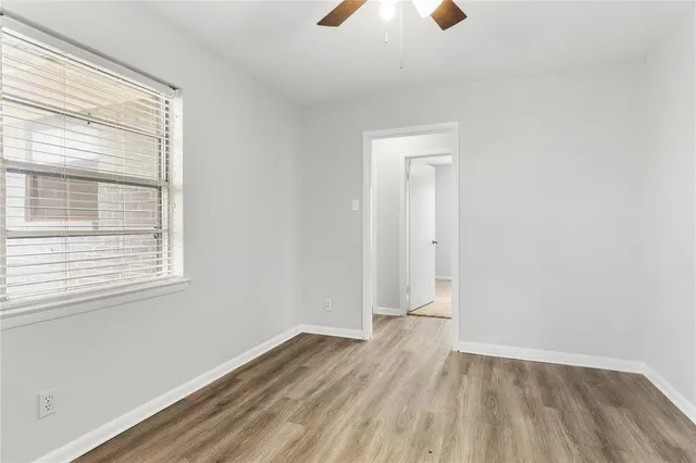 an empty room with a window and a fan