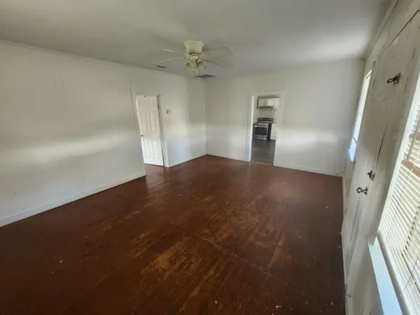 an empty room with wooden floor and windows