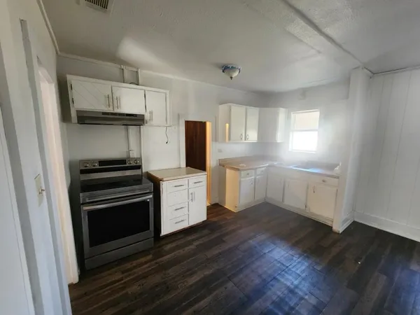 a kitchen with granite countertop stainless steel appliances a stove refrigerator sink and cabinets