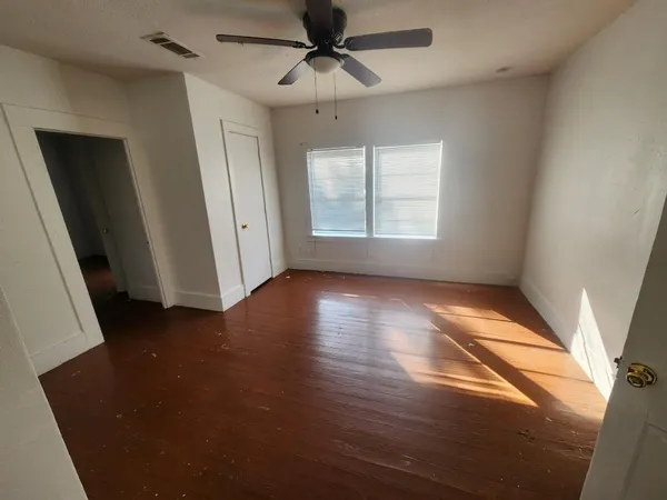an empty room with wooden floor and windows