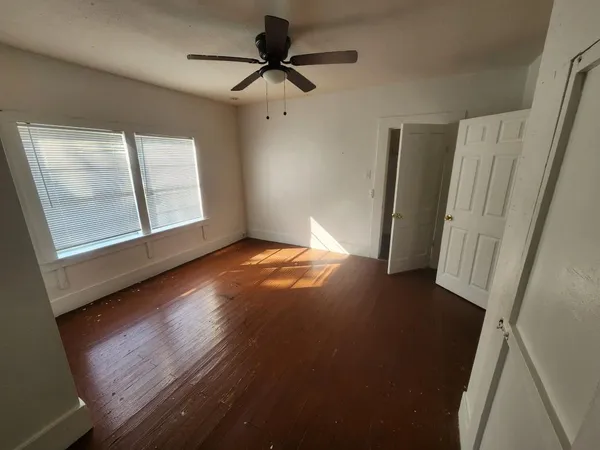 an empty room with wooden floor and windows