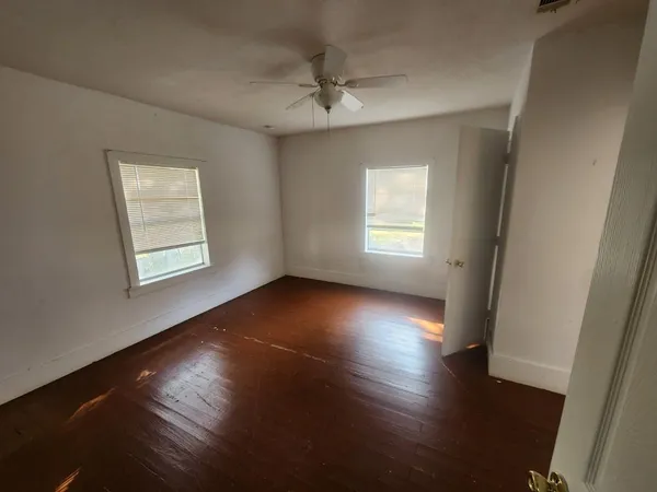 an empty room with wooden floor and windows