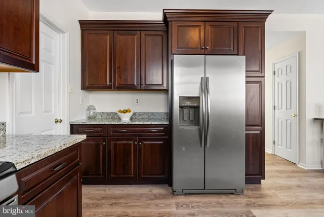a kitchen with stainless steel appliances granite countertop a table chairs stove and refrigerator