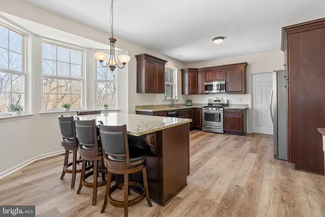 a large kitchen with stainless steel appliances kitchen island granite countertop a refrigerator a oven and a view of living room