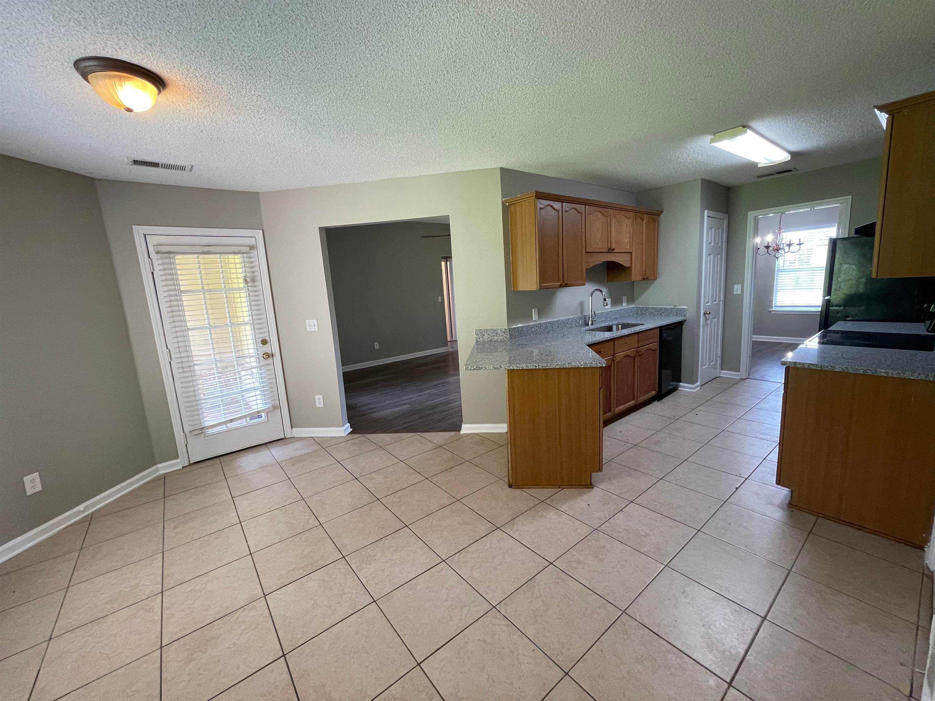 4580 Sun Ridge Drive Memphis, TN 38128 - Photo 7 of 16 Kitchen featuring black appliances, a chandelier, a textured ceiling, light tile patterned flooring, and a peninsula