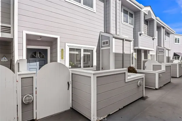 a view of white house with stainless steel appliances wooden floor and iron fence
