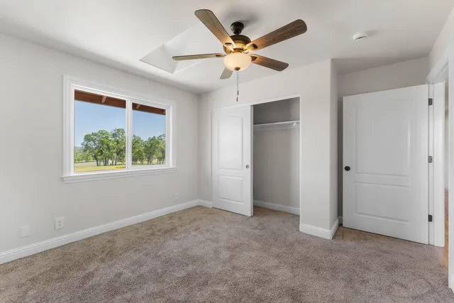 an empty room with a ceiling fan and window