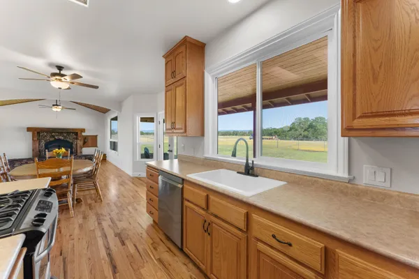 a open kitchen with granite countertop a sink dishwasher a stove and a dining table with wooden floor