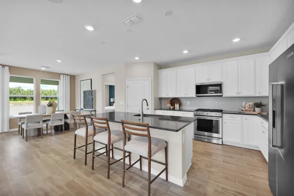 a kitchen with stainless steel appliances a microwave a stove a refrigerator and a microwave with wooden floor