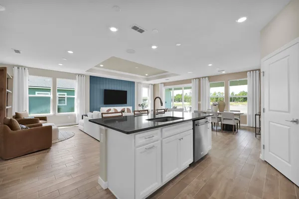 a kitchen with stainless steel appliances granite countertop a stove top oven a sink dishwasher a dining table and chairs with wooden floor