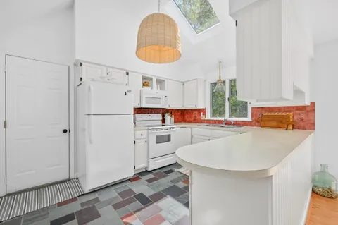 a kitchen with white cabinets and refrigerator