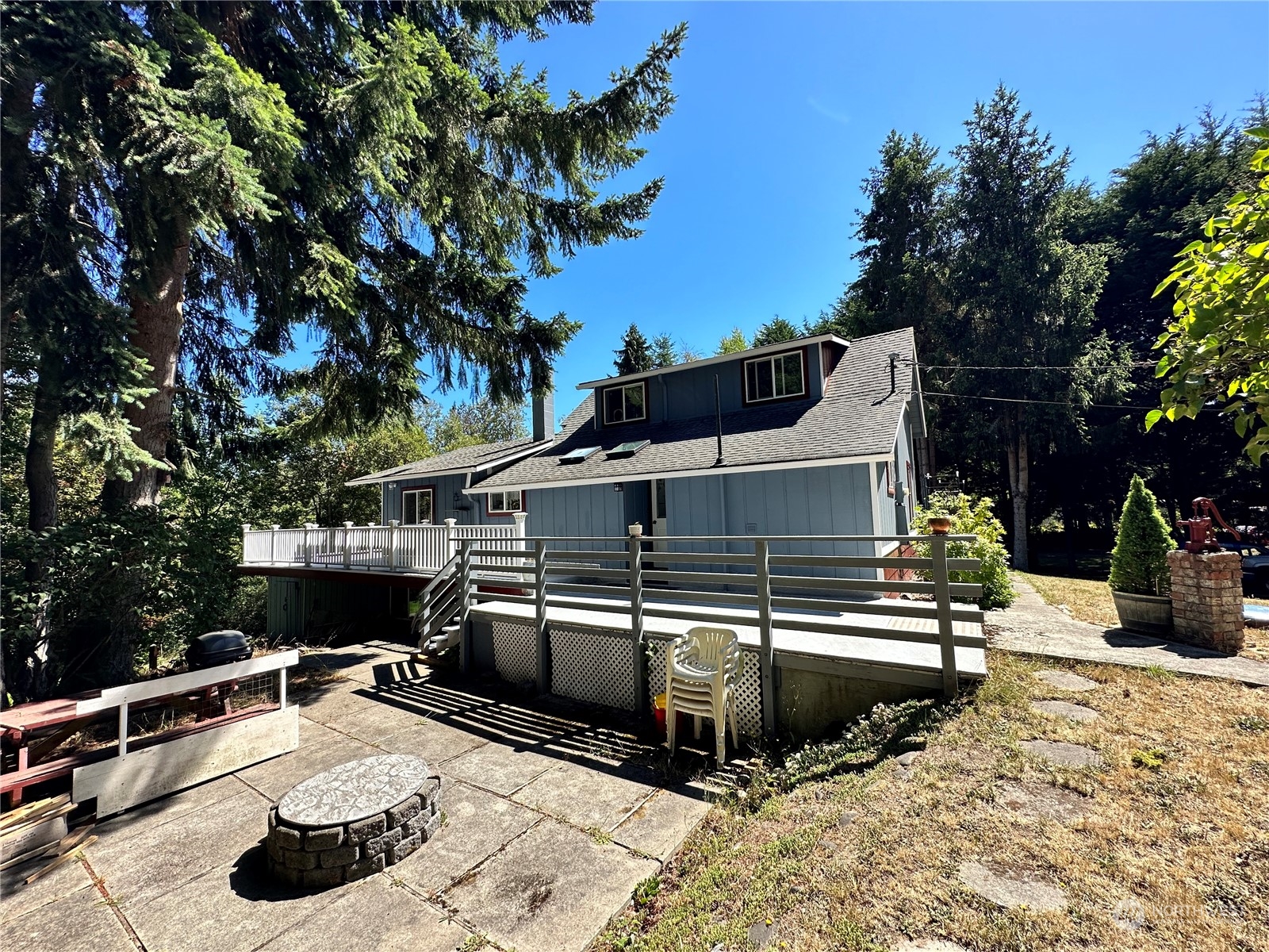 732 Gasman Road Port Angeles, WA 98362 - Photo 4 of 35 a view of a roof deck with table and chairs a barbeque with potted plants and large trees