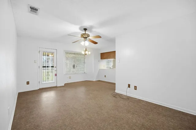 an empty room with windows and ceiling fan