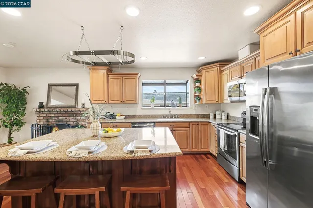 a kitchen with stainless steel appliances granite countertop a sink a stove and refrigerator