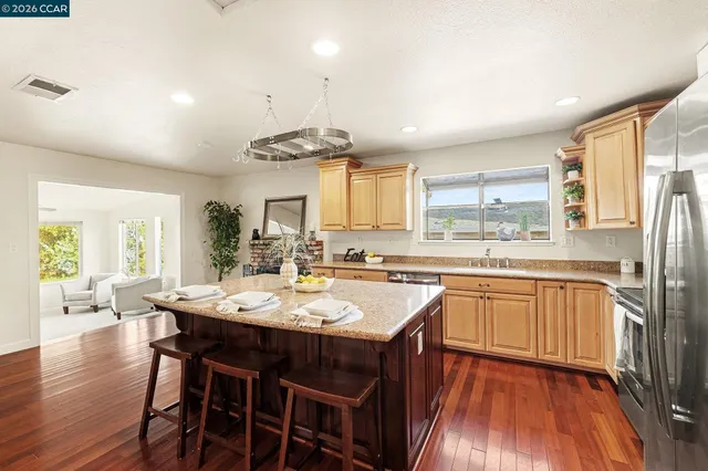 a kitchen with stainless steel appliances granite countertop a stove a sink dishwasher a stove a dining table and chairs with wooden floor