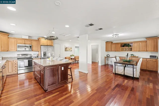 a large kitchen with stainless steel appliances refrigerator wooden floor and cabinets