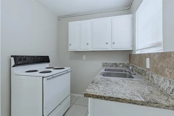 a kitchen with granite countertop white cabinets and a stove