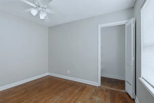 a view of an empty room with wooden floor and a window