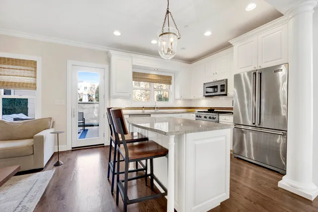 a kitchen with stainless steel appliances granite countertop a refrigerator a stove a sink dishwasher a dining table and chairs with wooden floor