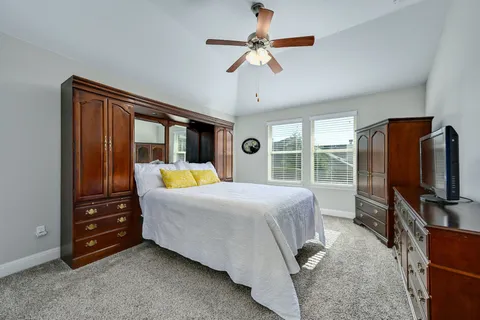 a bedroom with a bed and a flat tv screen on dresser