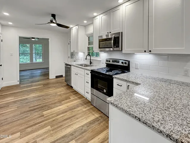 a kitchen with stainless steel appliances granite countertop a sink stove microwave and cabinets