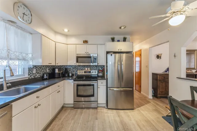 a kitchen with kitchen island granite countertop a refrigerator oven a sink and dishwasher a oven with wooden floor