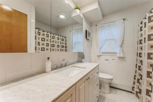 a bathroom with a granite countertop sink a toilet a mirror and shower