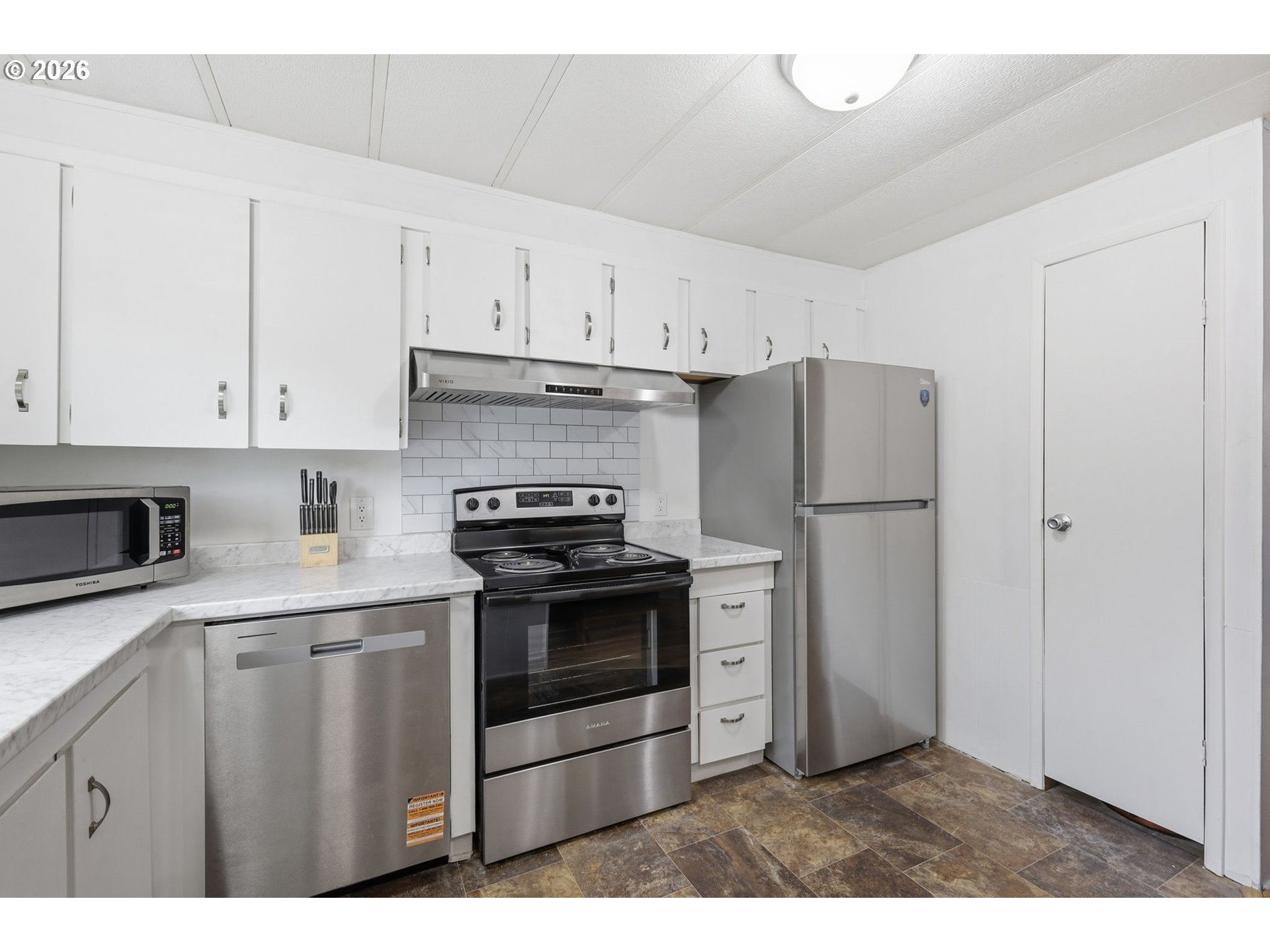 1600 Rhododendron Drive, Unit 76 Florence, OR 97439 - Photo 9 of 36 a kitchen with stainless steel appliances granite countertop a refrigerator a stove a sink and white cabinets