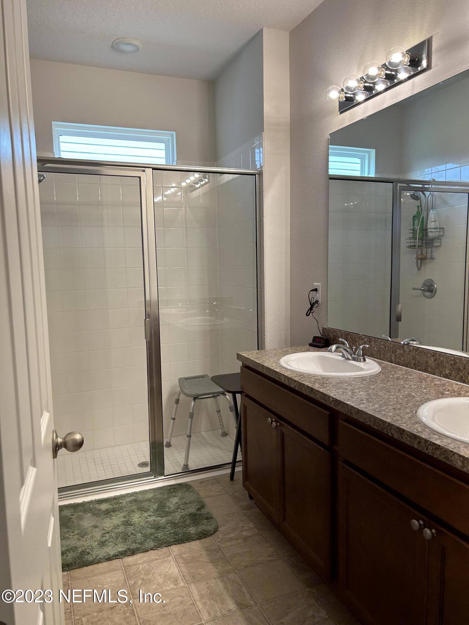 7109 Red Timber Road Jacksonville, FL 32244 - Photo 8 of 18 a bathroom with a granite countertop sink a mirror and a shower