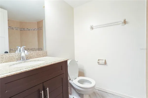 a bathroom with a granite countertop sink a toilet and a mirror