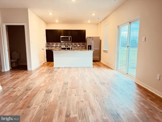 a large kitchen with stainless steel appliances a large counter top space a refrigerator and a fireplace