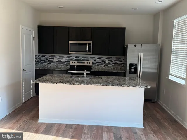 a kitchen with kitchen island granite countertop a stove and a microwave