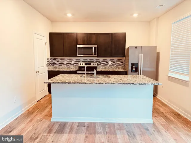a living room with stainless steel appliances kitchen island granite countertop a stove and a sink