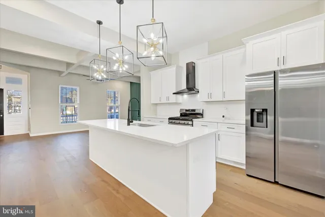 a kitchen with kitchen island granite countertop stainless steel appliances a sink a stove a refrigerator cabinets and wooden floor